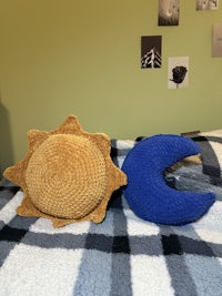 a blue and white crocheted evil eye pillow on a bed